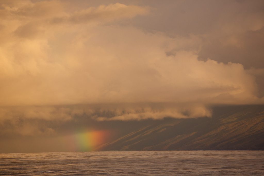 A rainbow along the base of the West Maui coastline as seen from offshore. 